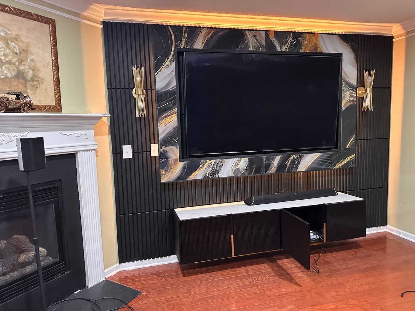 Black fluted panels framing a dramatic black and gold marble field, with warm cove lighting above and a fluted base cabinet