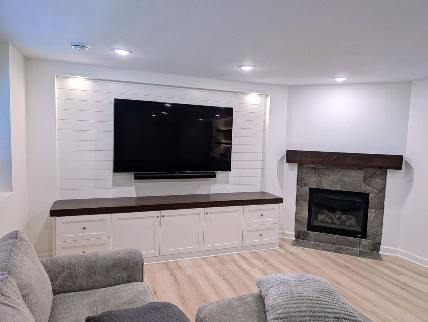 White horizontal shiplap media wall with recessed lighting, a walnut counter and built-in cabinets below